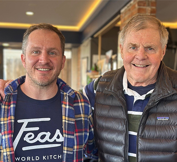 مجموعة من خمسة أشخاص يقفون معًا في ممر مستشفى مضاء بإضاءة ساطعة، ويبتسمون للكاميرا. اثنان يرتديان سماعات طبية وملابس طبية، وواحد يرتدي قميصًا رياضيًا من جامعة غونزاغا، والآخرون يرتدون ملابس غير رسمية أو مهنية، مما يمثل مزيجًا من الطلاب والمهنيين الصحيين.